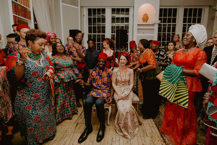a just married couple sits in two chairs surrounded by wedding guests