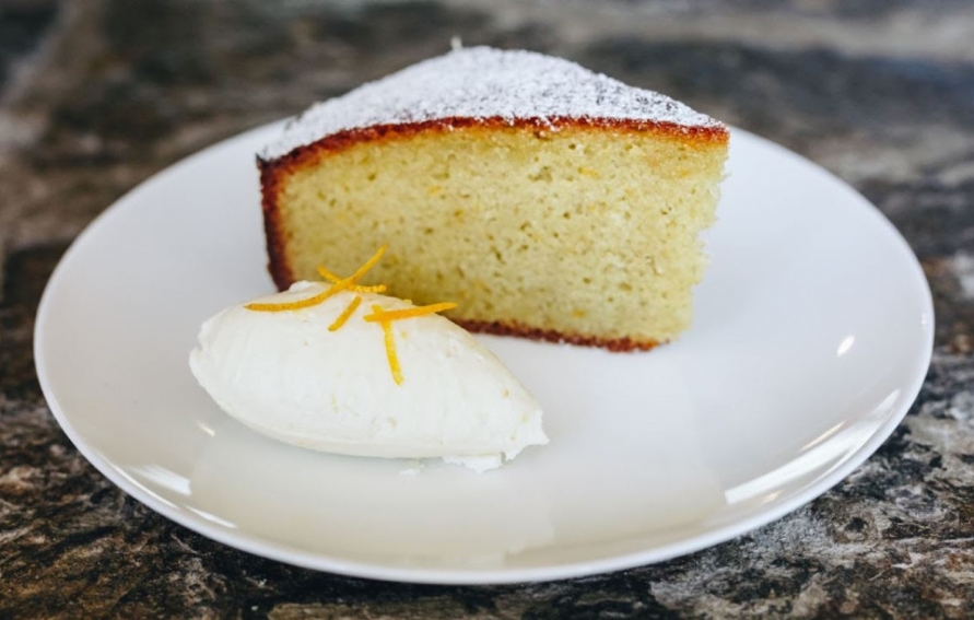 a slice of orange olive oil almond torte on a small white plate